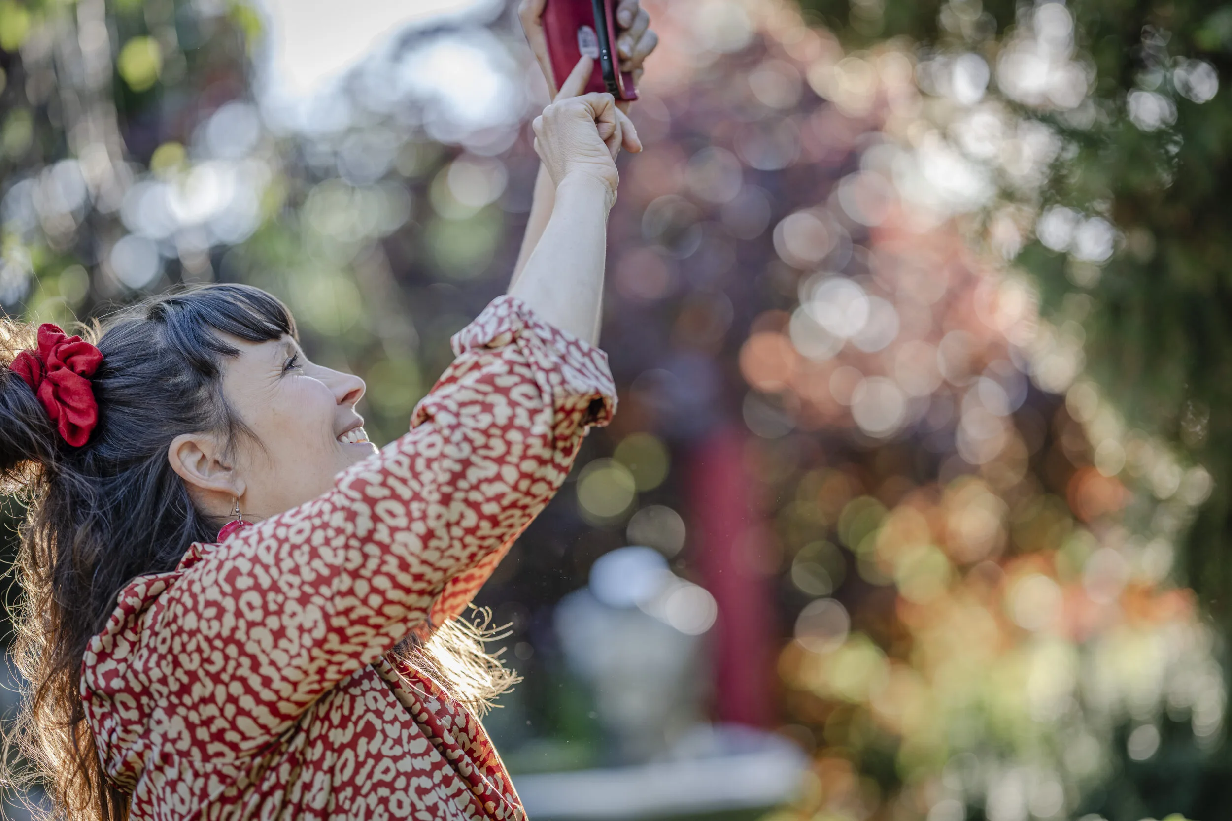 A woman reaching upward in a sunlit garden