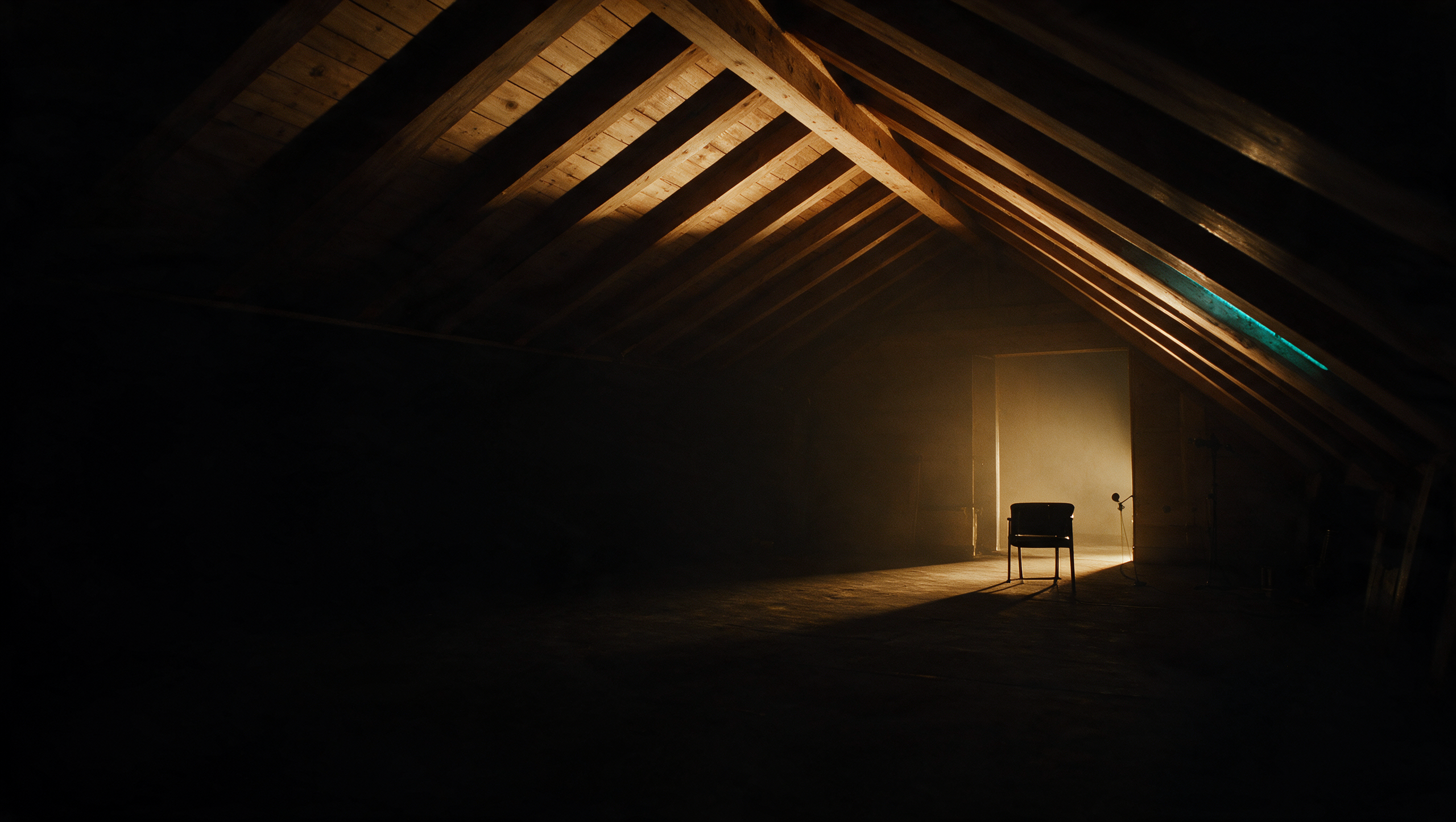 A dark production studio with wooden beams, an empty chair and a precise light edge