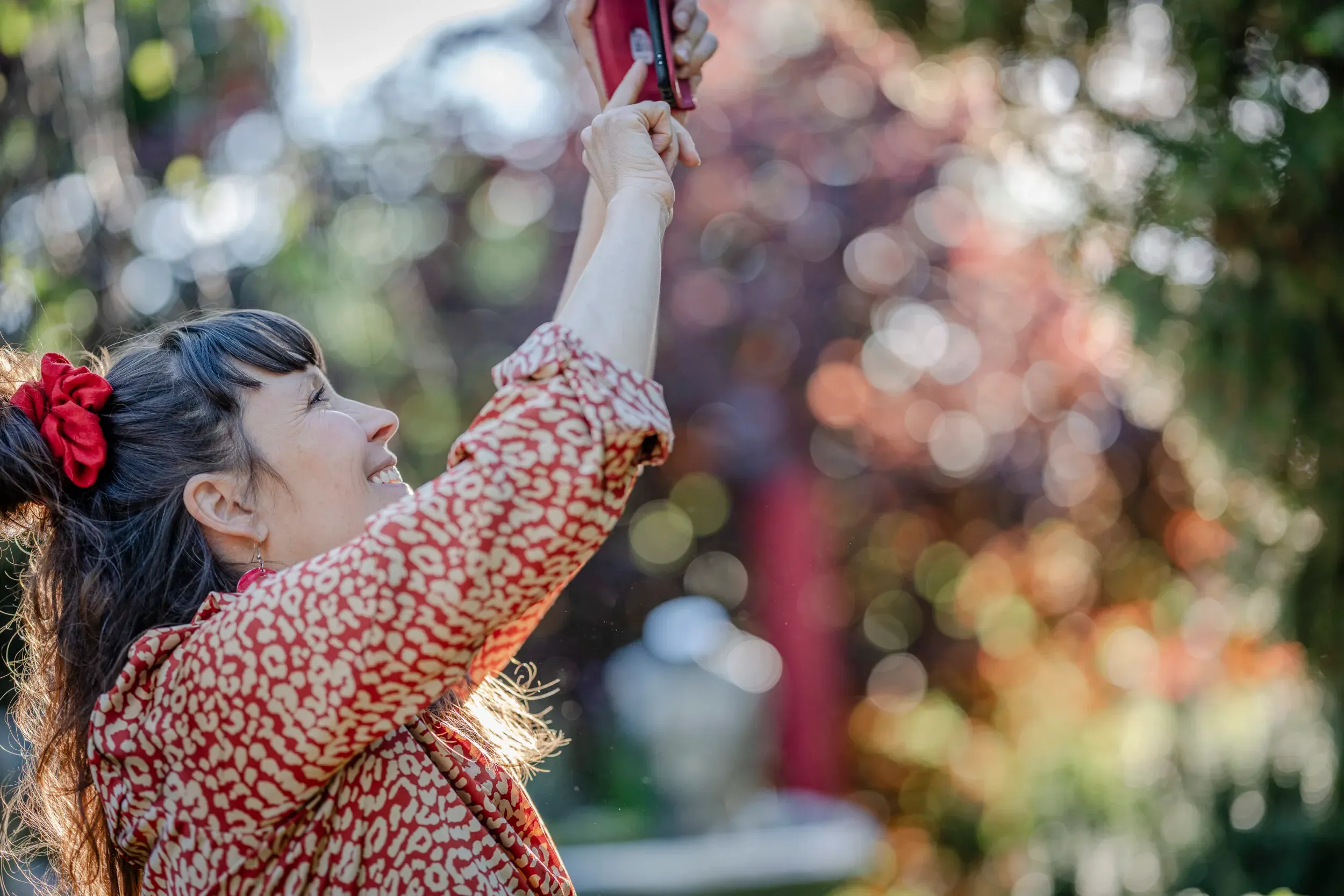 A woman reaching upward in a sunlit garden